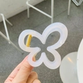 Elegante pinza per capelli a farfalla bianco crema con molla dorata tenuta in mano - Bianco Gelatina