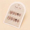 Close-up of nude cat-eye nail tips with black bow and polka dot patterns on display card - By1734 / Glue Type