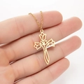 Close-up of a gold cross pendant featuring hollow rose petals held in a hand - Rose