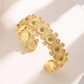 Luxurious gold-tone daisy bangle featuring green gemstones and micro-set zircon stones - Gold