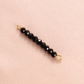 Detail of faceted black crystal beads with gold metal connectors on pink fabric - Black