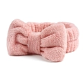 Detailopname van een roze koraalvlies haarband met een grote pluche strik decoratie - Perzikroze