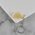 Realistic PVC garlic clove keychain with a silver metal ring on a marble surface - Garlic Clove - Keychain / Cream White
