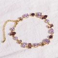 Detailed view of golden bracelet with purple stones on textured white fabric - Purple Zircon - Gold