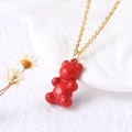Colorful red gummy bear pendant with gold chain necklace on white marble background - Red