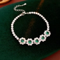 Détail d'un bracelet fleur en argent avec pierres vertes sur un fond en velours vert - Argent-Vert