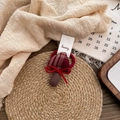 Detail of fabric mushroom hair tie with brown plaid pattern and red bow on woven mat - Plaid Mushroom Hair Tie