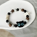 Detailansicht eines Keramikperlen-Armbands mit schwarzer Katze und weißem Sternanhänger - 15 Katzenkopf Schwarz Blaue Augen