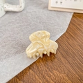 Mini cream acetate hair claw clip with swirl pattern on a dark wooden background - Off-white