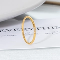 Minimalistischer 18K vergoldeter Titanring mit drei Zirkoniasteinen auf weißem Hintergrund - US 6 / Runde Spule Drei Steine Gold