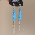 Detailansicht blauer Kristallohrringe mit langen goldenen Kettenquasten und Glitzereffekt - Hellblau