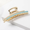 Detail of golden metal hair claw clip featuring a blue enamel stripe for elegant styling - Blue
