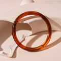 Detailed view of an amber acrylic bangle with tortoise shell pattern on geometric props - Amber