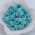 Dettaglio di perline a forma di fiore in ceramica blu cielo in una ciotola bianca per DIY - Howlite Blu
