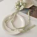 Detail of mint green satin scrunchie with long ribbons on a minimalist white surface - Bean Paste Green