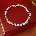 Vue macro d'un bracelet argenté en forme de X avec zircon bleu et blanc sur coffret - Argenté