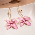 Gros plan détaillé des boucles d'oreilles fleur en émail rose sur un plat blanc - Tige en argent 925 / Rose