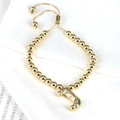 Detail of golden beaded bracelet with zircon-studded letter J pendant and adjustable clasp - Letter J