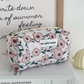 Detailopname van gewatteerde make-uptas met bloemenpatronen en een stevige metalen rits - Achthoekig Tasje