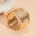 Detalle de cerca del brazalete ancho geométrico dorado sobre un fondo de estilo minimalista - Cuff Bracelet / Dorado