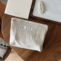 Detailopname van beige linnen zakje met geweven label op een rustieke houten tafelblad - Natuurlijk Linnen Paisley