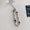 Detail shot of Y2K style phone charm with white pearls, black dice, and butterfly pendant - Dice Silver Bow