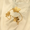 Detail van 18k vergulde roestvrijstalen bloemenarmband op elegante beige zijden achtergrond - Gouden Drie-Bloemen Open Armband