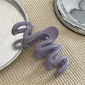 Close-up of purple wavy hair claw clip with smooth plastic finish on a textured surface - Purple