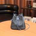 Blue denim drawstring bucket bag on a round wooden table for a trendy minimalist look - Blue