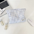 Detailed view of checkered blue makeup bag with woven fabric texture and side brand tag - Blue White Plaid