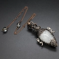 Macro shot of clear crystal pendulum pendant with vintage bronze hollow metal frame and chain - Clear Quartz + Pendulum Chain