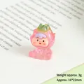 Close-up of a mini resin dragon fruit figurine with a pink bow on an open book - Luminous Dragon Fruit