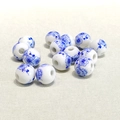 Macro shot of 10mm blue and white floral ceramic beads scattered on beige fabric - 10mm / Blue and White Large Plum Blossom