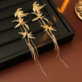 Detailed view of gold bamboo leaf earrings with long tassels on a professional jewelry stand - Gold