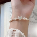 S925 silver bracelet featuring a cat shell charm and freshwater pearls worn on a wrist - 925 Silver / Silver