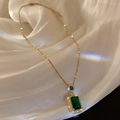 Close-up of emerald square pendant with diamonds on elegant white silk background - Green Square Necklace