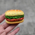 Realistic 3D resin hamburger fridge magnet accessory shown in a handheld close-up view - Rectangular Hamburger