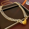 Macro di una collana di strass a tre strati con un grande ciondolo a cuore dorato lucido - Oro
