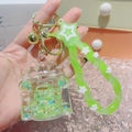 Macro detail of a luminous drifting bottle keychain with green sequins and star charm - Castle Green