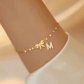 Elegant gold bow bracelet featuring a crystal-encrusted M letter pendant charm - Style 6