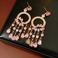 Détail de boucles d'oreilles pompon en cristal rose avec finition dorée sur écrin en cuir - Or-Rose (Tige en argent)