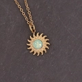 Dettaglio del ciondolo a girasole dorato con gemma verde chiaro e catena metallica - Sole Verde