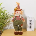 Detail of harvest scarecrow doll featuring telescopic legs and sunflower hat on a desk - Green Overalls Men's Plush Toy
