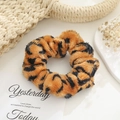 Detail of leopard print plush scrunchie with soft fur texture on white surface - Leopard Print