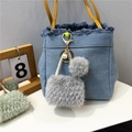 Detailed view of grey plush keychain with blue denim bag charm and pearl accents - Gray