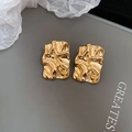 Detailed macro view of irregular crumpled gold stud earrings with polished texture - Gold