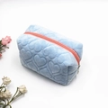 Dettaglio della borsa di peluche celeste con trama trapuntata a cuore e zip rosa - Azzurro