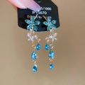 Primer plano de pendientes de flores de cristal azul brillante con acabado dorado - Pin de Plata Flor Azul