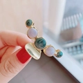 Detail of a large gold metal hair claw clip featuring green and purple marble texture - Blue-Green Marble