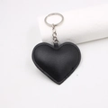 Llavero de corazón en cuero negro con anillo metálico y costuras finas para bolsos - Negro
